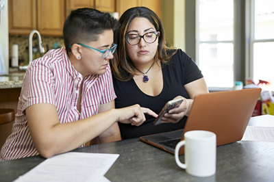 Adults with phone and laptop iStock 1411368474